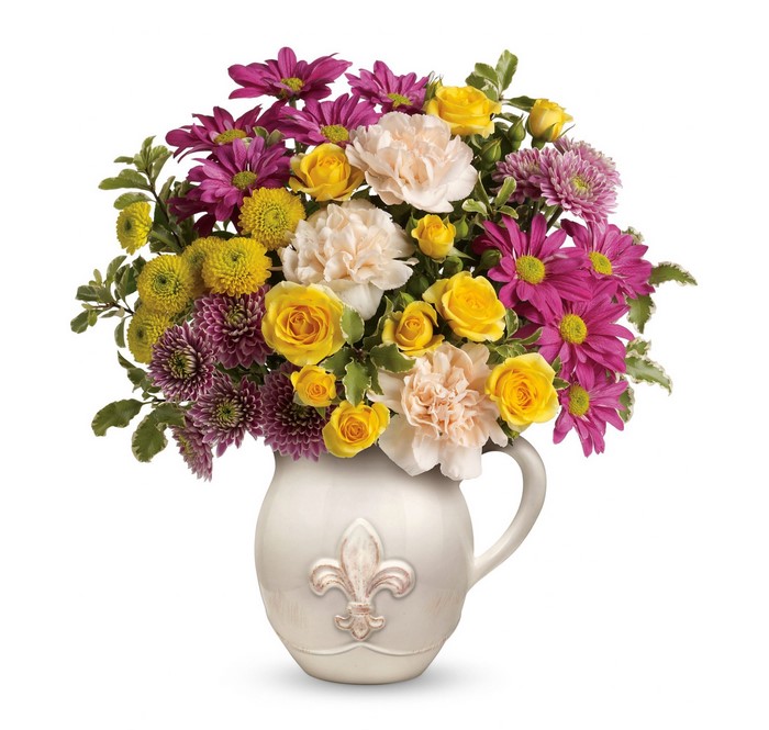 Yellow roses, purple chrysanthemums, and pink carnations in a decorative pitcher vase