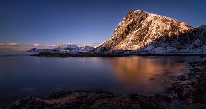 Snow-capped mountains reflecting in a calm sea in Lofoten, Norway