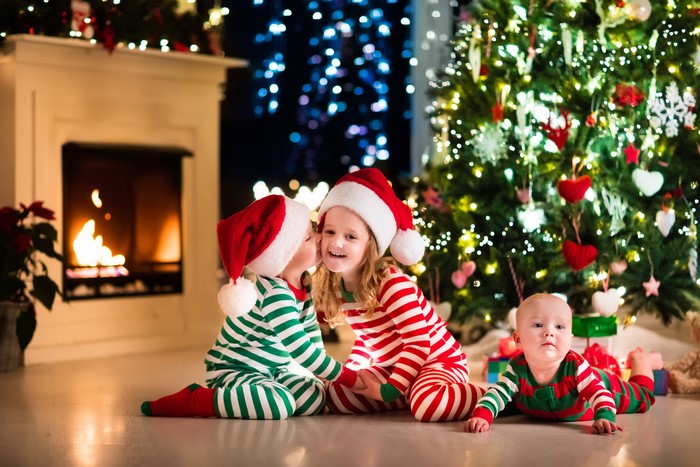 Three Children in Christmas Pajamas by Fireplace and Tree