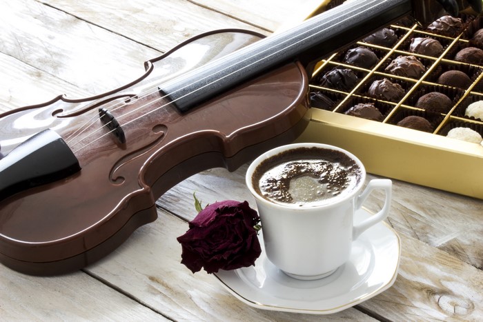Still-life of violin, coffee, chocolates, and rose