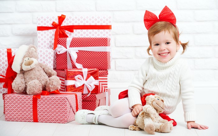 Little girl with teddy bear and Christmas gifts