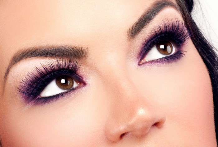 Close-up of a woman's eyes with purple eyeshadow and false eyelashes