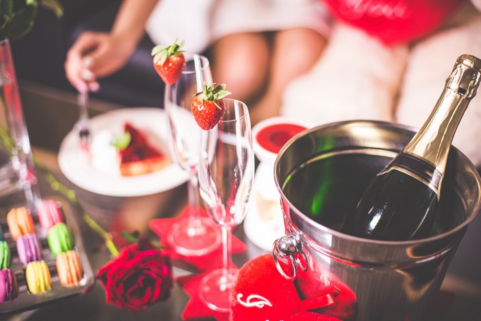 Champagne bottle in bucket with strawberries and cake