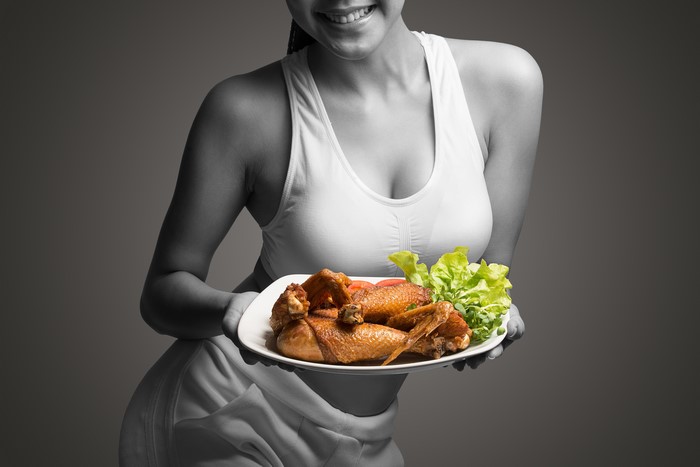 Woman in Singlet Holding Plate of Roast Chicken