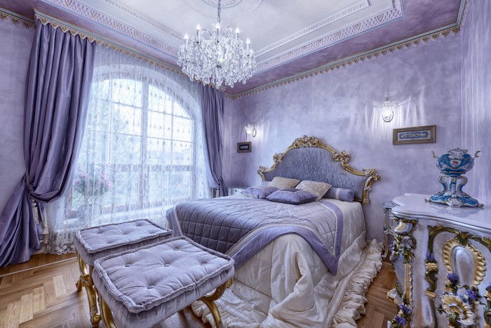 Luxurious bedroom with a large arched window and chandelier