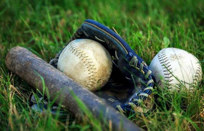 Baseball bat, baseballs, and glove on grass