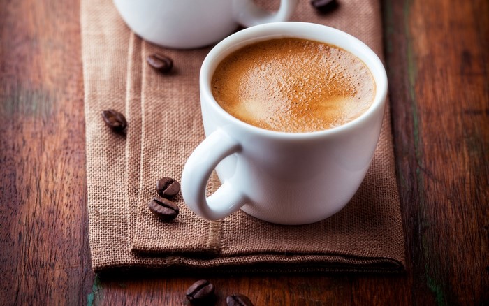 Espresso coffee in a white cup with coffee beans