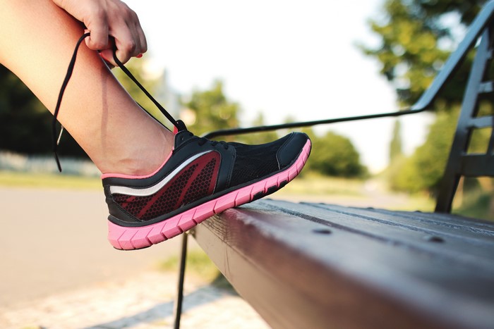 Person Tying Athletic Shoe on Bench