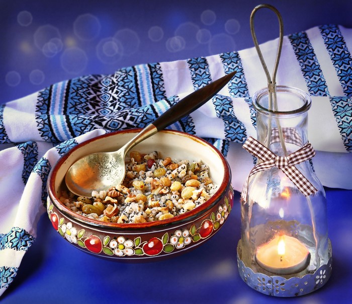 Kutia with spoon and candle lantern on embroidered cloth