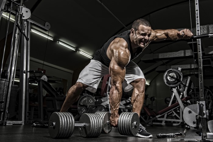Bodybuilder performing dumbbell row in a gym