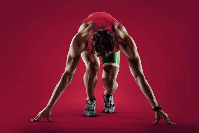 Runner in starting pose on red background