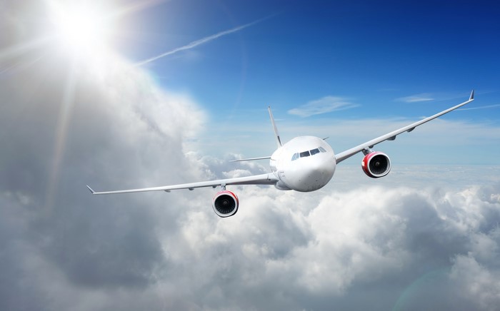 Airplane flying through clouds under the sun
