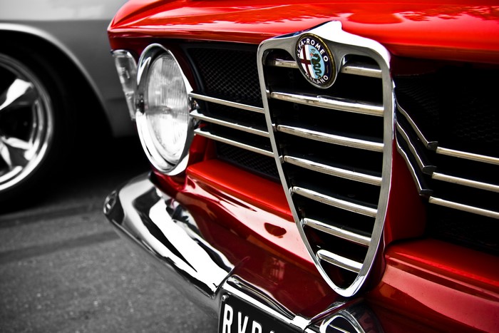 Close-up of a red Alfa Romeo car grille and headlight