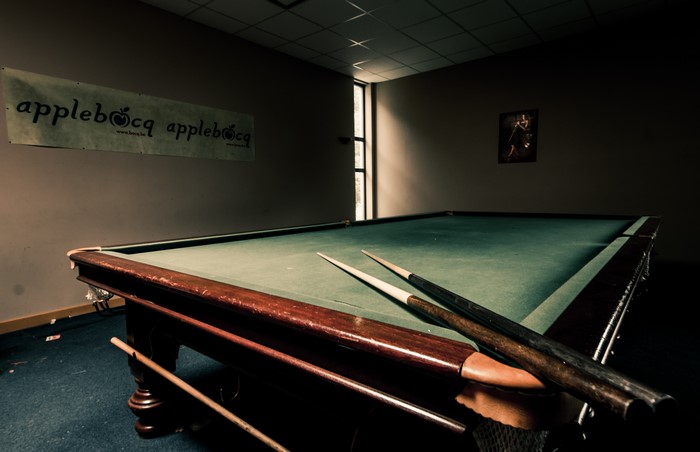 Billiard table with cues in a dimly lit room