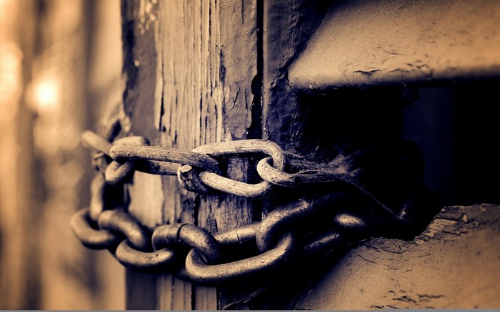 Close-up of a rusty chain on a wooden post