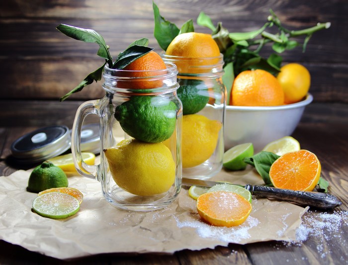 Citrus fruits in jars and on a wooden table
