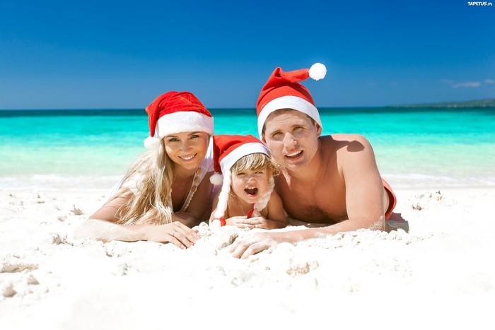 Family in Santa hats on a tropical beach