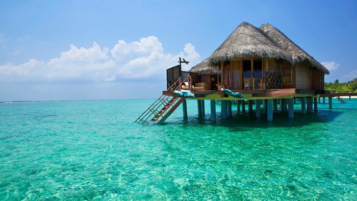 Overwater bungalow on turquoise water under blue sky