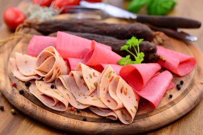 Sliced meat products and sausage on a cutting board