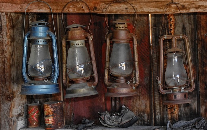 Four old kerosene lanterns hanging on a wooden wall