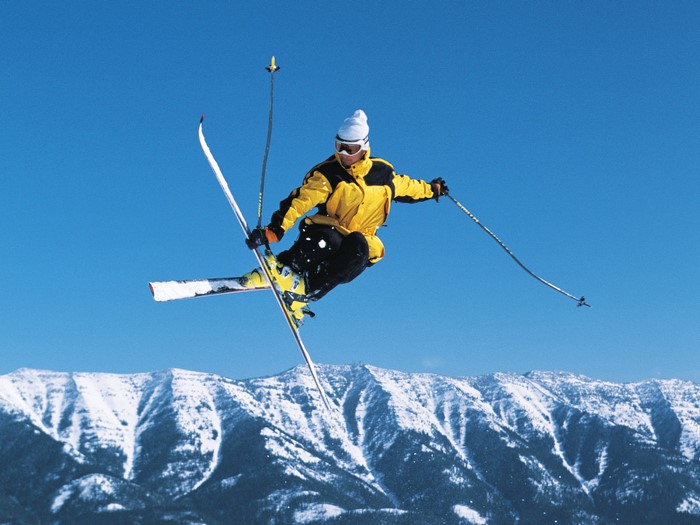 Skier performing a jump over snowy mountains
