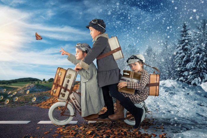 Three girls on a scooter with suitcases, transitioning seasons