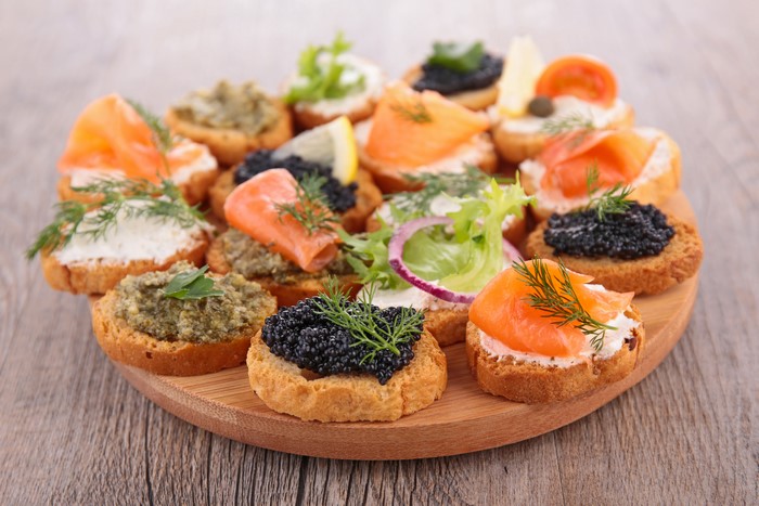 Assorted canapés with salmon and caviar on a wooden board