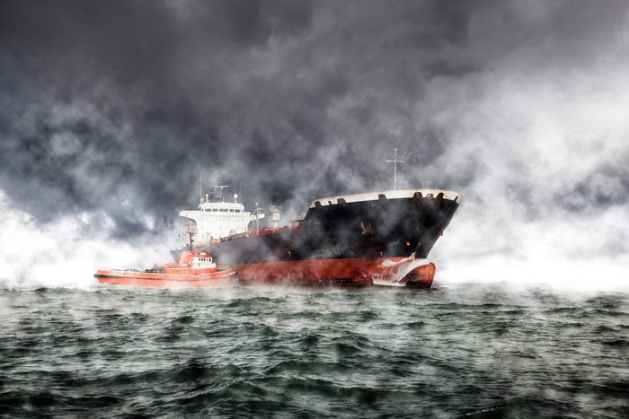 Tanker ship and tugboat in stormy sea