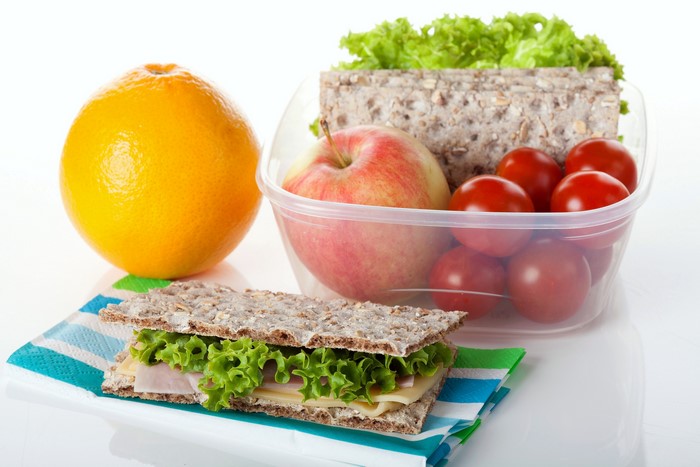 Lunchbox with sandwich, apple, orange, and tomatoes