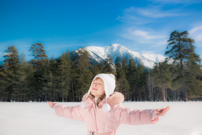 Girl in Winter Hat and Snowsuit in Snowy Mountains