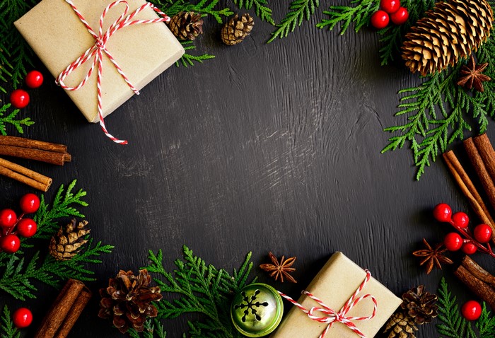 Christmas gifts, pine cones, cinnamon sticks, and berries on a dark background