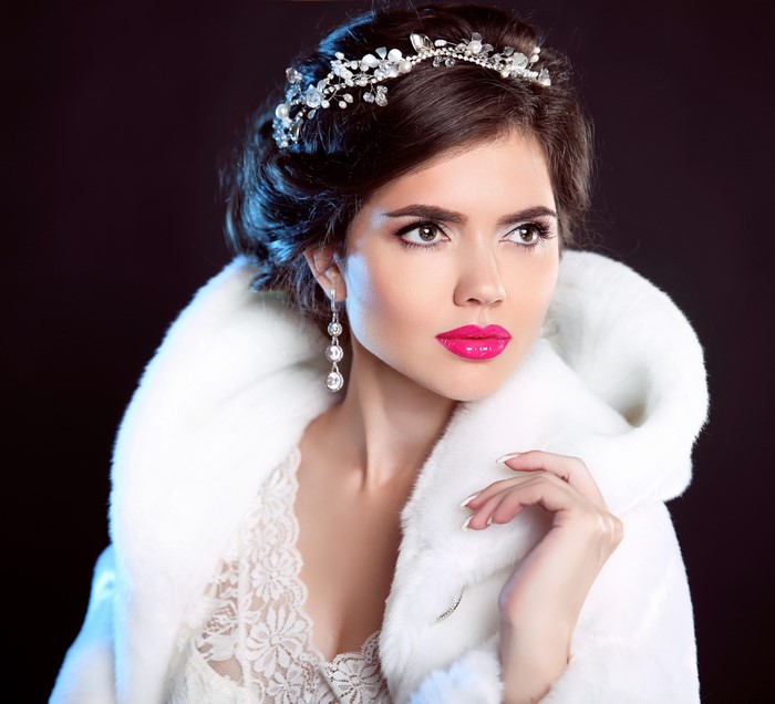 Woman with tiara and earrings on black background