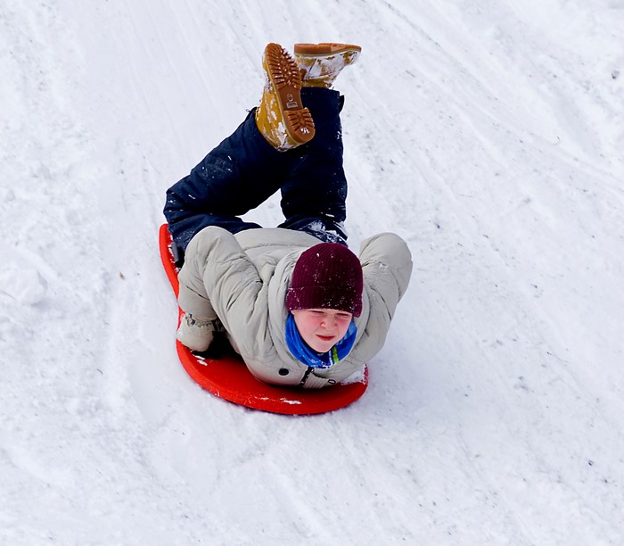 Boy sledding down a snowy hill