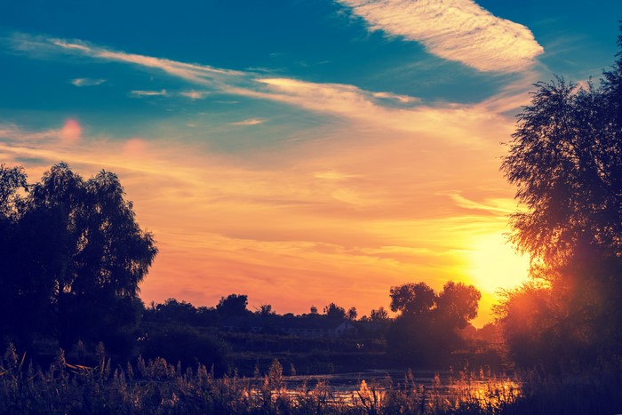 Sunset over a pond with trees and clouds