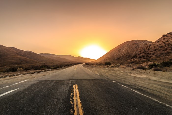 Road through desert mountains at sunset