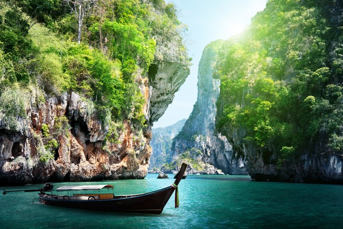 Longtail boat in a tropical bay with limestone cliffs