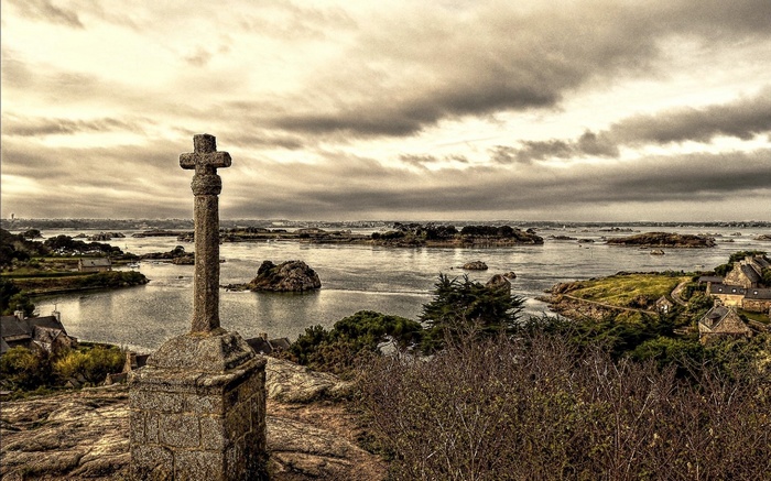 Stone cross overlooking a coastal village and islands