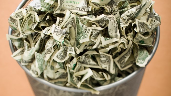 Crumpled Dollar Bills in a Trash Can
