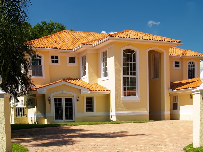 Yellow mansion with orange tile roof and palm trees