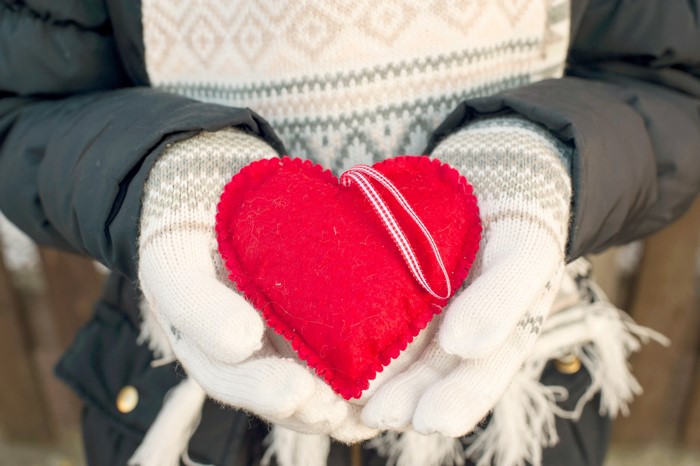 Person holding a red heart ornament