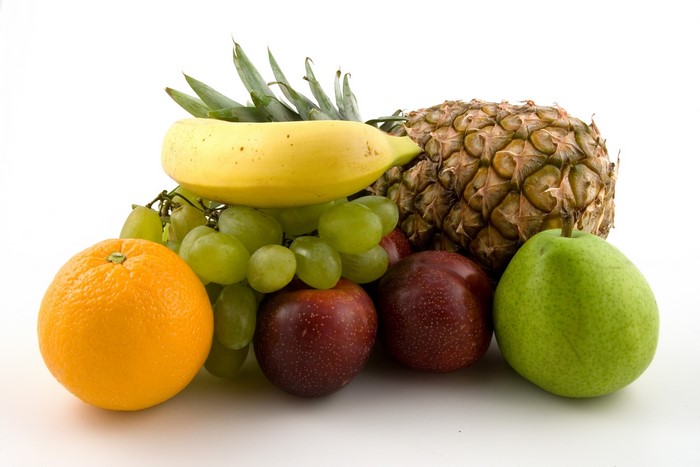 Assortment of fresh fruits including pineapple, banana, grapes, orange, apples, and pear