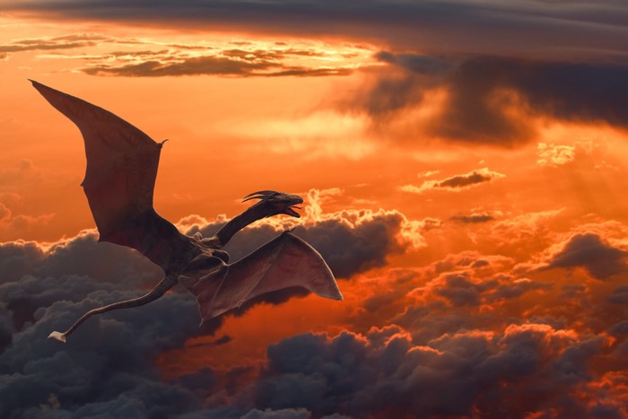 Dragon flying through clouds at sunset