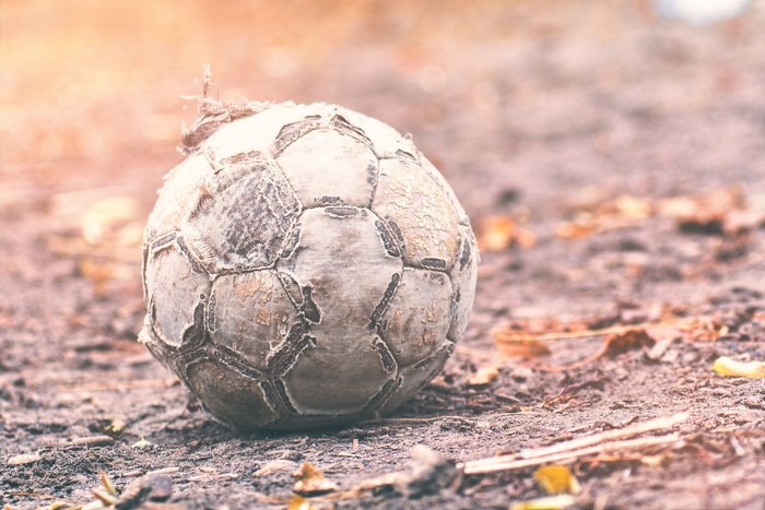 Old, worn soccer ball on the ground