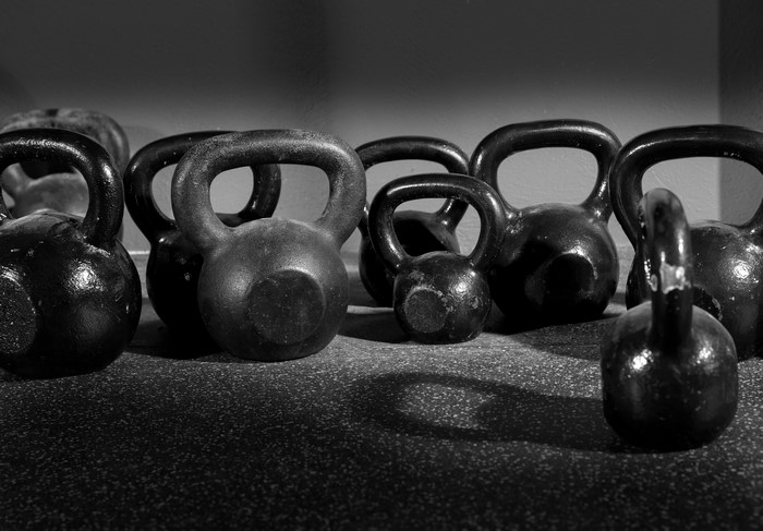 Many black kettlebells on a gym floor