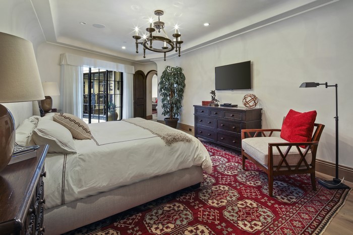 Bedroom with bed, chandelier, carpet, and armchair