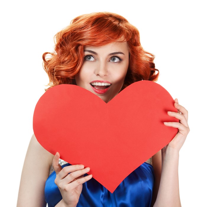 Redhead girl holding a red heart on white background