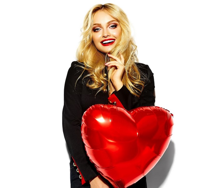 Blonde woman holding a red heart balloon