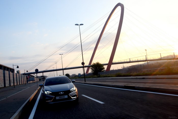 Lada Vesta driving on a road near a bridge