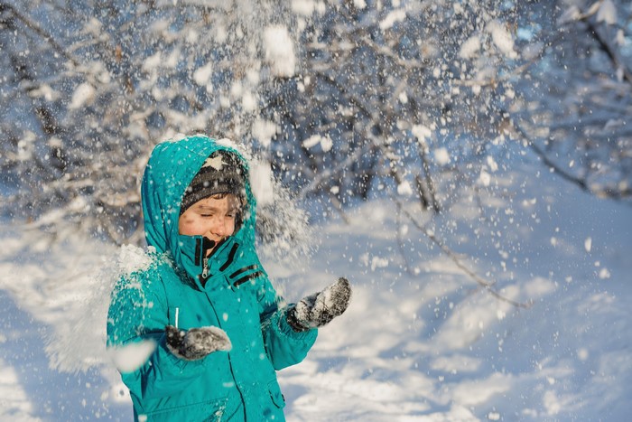 Boy in a blue jacket throwing snow
