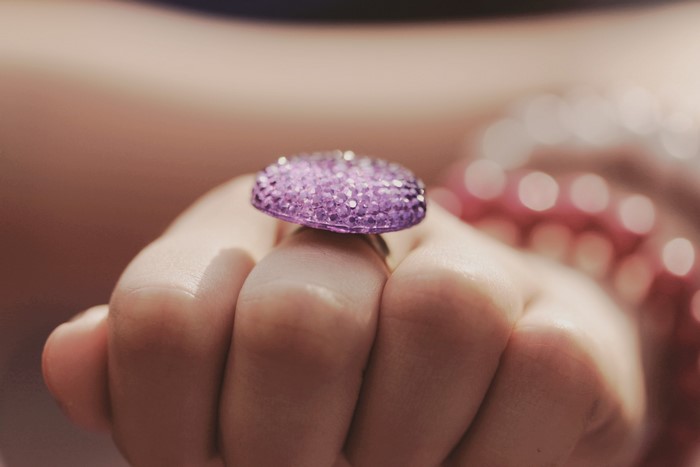 Close-up of a hand wearing a purple gem ring